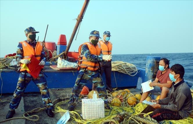 Lực lượng cảnh sát biển Việt Nam hướng dẫn ngư dân rửa tay khử trùng để phòng dịch COVID-19. Ảnh: TTXVN phát