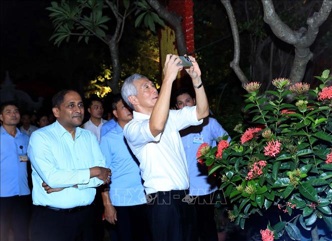 Singapore Prime Minister Lee Hsien Loong sometimes stops to take photos of Hanoi night with his phone. VNA Photo: An Đăng