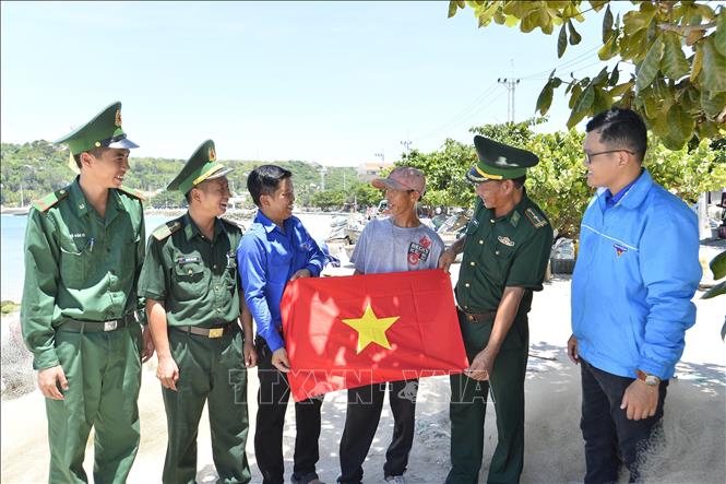 Đoàn viên, thanh niên Xã đảo Nhơn Châu cùng đoàn viên, thanh niên Đồn Biên phòng Nhơn Châu trao tặng cờ Tổ quốc cho ngư dân. Ảnh: Minh Đức - TTXVN