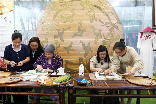 Bà Lê Thị Bích Trân (bên phải), Phu nhân Thủ tướng Phạm Minh Chính cùng bà Hà Tinh, Phu nhân Thủ tướng Singapore Lý Hiển Long trải nghiệm ghép tranh từ vải lụa vụn. Ảnh: Phạm Kiên - TTXVN