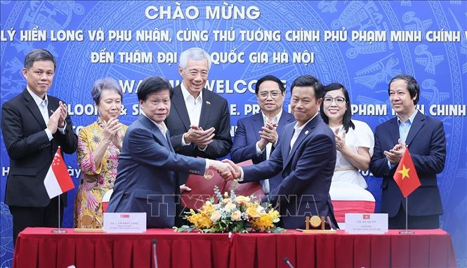 PMs Pham Minh Chinh and Lee Hsien Loong witness the signing of a cooperation agreement between VNU-Hanoi and Nanyang Technological University (TNU) of Singapore. VNA Photo: Dương Giang
