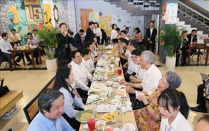 PMs Pham Minh Chinh and Lee Hsien Loong together with their spouses have lunch with the students. VNA Photo: Dương Giang