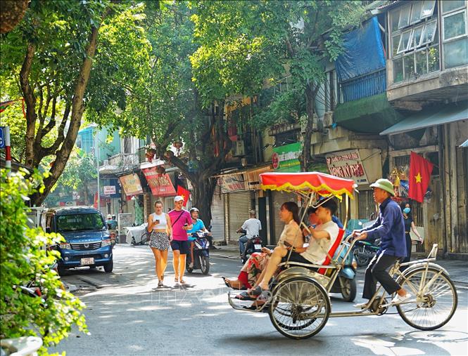 Du khách nước ngoài tận hưởng tiết trời Thu trong buổi sáng sớm của ngày Tết Độc lập ở Hà Nội. Ảnh: Khánh Hoà - TTXVN