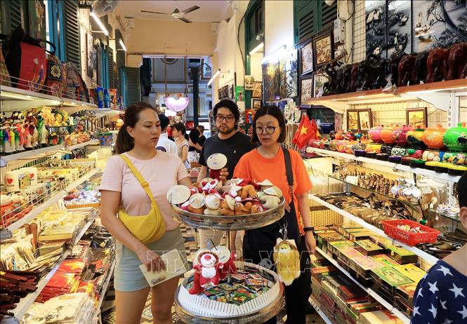 Khách quốc tế mua sắm tại quầy bán đồ lưu niệm trong Bưu điện Trung tâm Thành phố Hồ Chí Minh. Ảnh: Hồng Đạt - TTXVN
