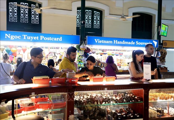 Khách quốc tế mua bưu thiếp, hoạt động đặc trưng khi đến với Bưu điện Trung tâm Thành phố Hồ Chí Minh. Ảnh: Hồng Đạt - TTXVN
