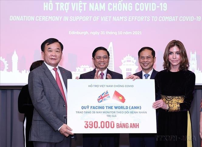 Thủ tướng Chính phủ Phạm Minh Chính chứng kiến Lễ trao quyên góp hỗ trợ Việt Nam chống dịch COVID-19 trong chuyến thăm làm việc tại Vương quốc Anh (2021). Ảnh: Dương Giang-TTXVN