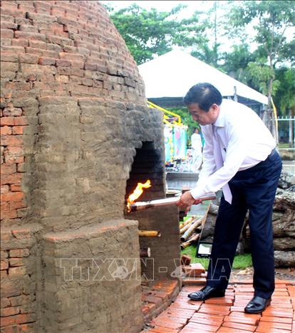 Bí thư Tỉnh ủy Vĩnh Long Bùi Văn Nghiêm thắp ngọn lửa nhóm lò gạch gốm truyền thống. Ảnh: Lê Thúy Hằng – TTXVN