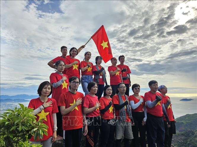 Nhóm du khách chinh phục núi Hoàng Ngưu Sơn và làm lễ chào cờ trên đỉnh núi. Ảnh: Phan Sáu - TTXVN