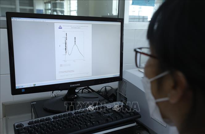 Cán bộ Trung tâm đọc kết quả kiểm nghiệm mẫu bằng phương pháp Quang phổ hấp thụ tử ngoại. Ảnh: Anh Tuấn - TTXVN 