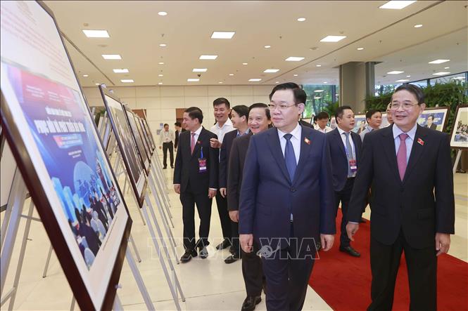Chủ tịch Quốc hội Vương Đình Huệ và đại biểu xem ảnh trưng bày tại diễn đàn. Ảnh: Doãn Tấn - TTXVN
