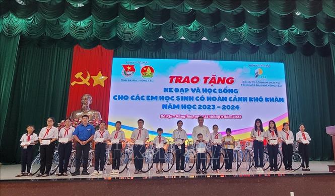 Đại diện lãnh đạo UBND tỉnh và đơn vị tài trợ trao xe đạp và học bổng cho các em học sinh có hoàn cảnh khó khăn trên địa bàn. Ảnh: Hoàng Nhị - TTXVN.