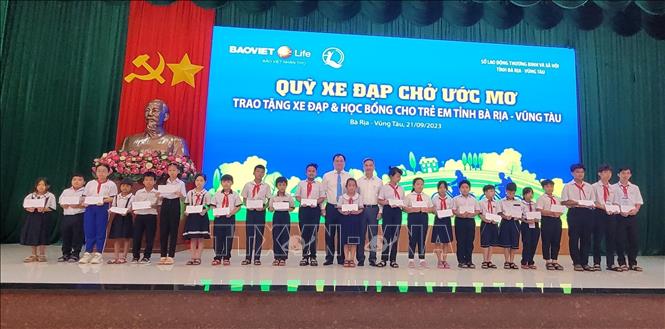 Ông Đặng Minh Thông, Phó Chủ tịch UBND tỉnh cùng đơn vị tài trợ trao học bổng cho các học sinh. Ảnh: Hoàng Nhị - TTXVN