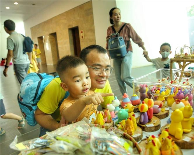 Em nhỏ thích thú với những món đồ chơi bằng đất nặn. Ảnh: Tuấn Đức - TTXVN