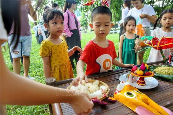 Các em nhỏ thích thú trước mâm cỗ Trung thu truyền thống. Ảnh: Tuấn Đức - TTXVN