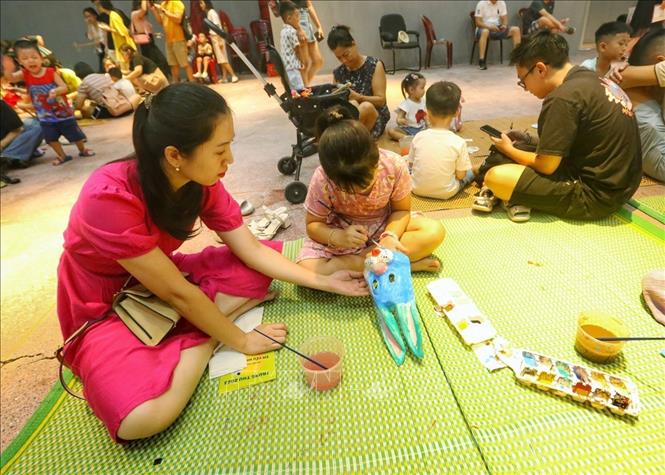 Các em nhỏ trải nghiệm tô màu mặt nạ giấy bồi. Ảnh: Tuấn Đức - TTXVN