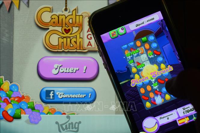 Người dùng chơi Candy Crush Saga trên điện thoại tại Rome, Italy. Ảnh: AFP/TTXVN