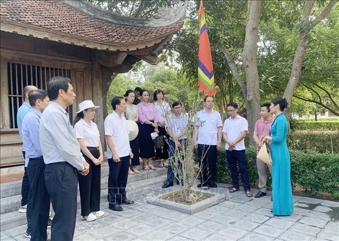 Hướng dẫn viên giới thiệu cho du khách các giá trị văn hóa, lịch sử của Khu di tích Nguyễn Du. Ảnh: Hữu Quyết - TTXVN
