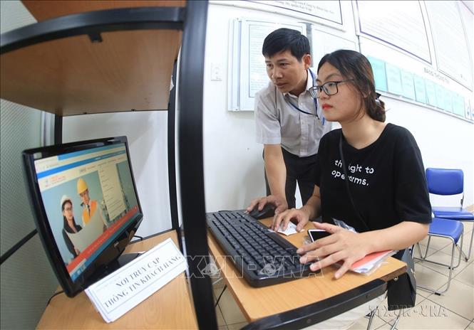 Hướng dẫn người dân thực hiện giao dịch điện tử các dịch vụ điện tại Phòng giao dịch khách hàng thuộc Tổng Công ty Điện lực TP Hồ Chí Minh. Ảnh: Ngọc Hà - TTXVN