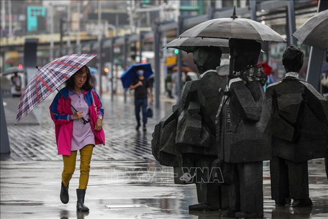 Người dân di chuyển trong mưa do ảnh hưởng của bão Koinu ở thành phố Cơ Long, vùng lãnh thổ Đài Loan (Trung Quốc), ngày 5/10/2023. Ảnh: AFP/TTXVN