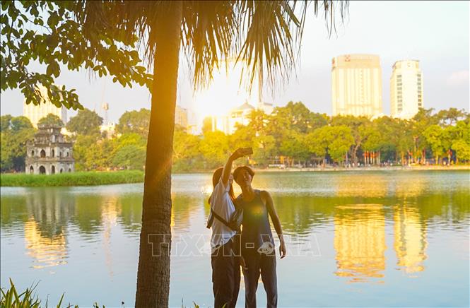 Du khách nước ngoài lưu lại khoảnh khắc mùa Thu bên hồ Hoàn Kiếm. Ảnh: Khánh Hoà - TTXVN