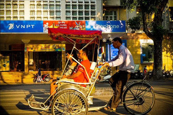 Du khách trải nghiệm ngồi xích lô tham quan Hà Nội giữa tiết Thu. Ảnh: Khánh Hoà - TTXVN