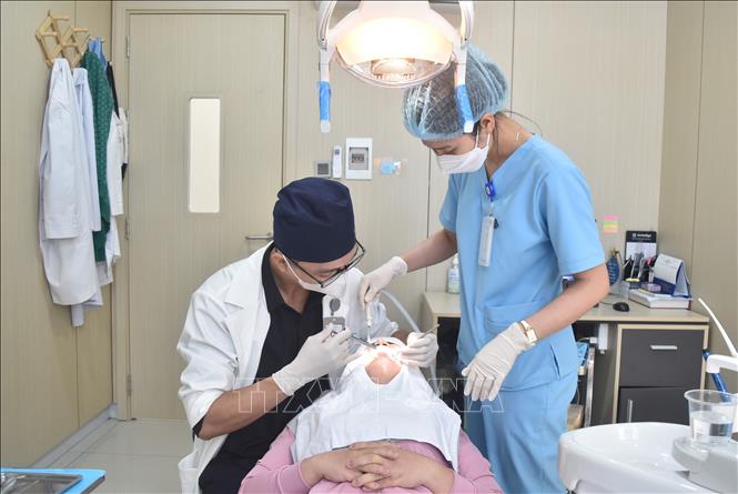 Anh Lê Bá Huỳnh Đức đang công tác tại Khoa răng hàm mặt, Bệnh viện Đại học Y Dược Buôn Ma Thuột (thành phố Buôn Ma Thuột) thăm khám cho bệnh nhân. Ảnh: Nguyên Dung – TTXVN