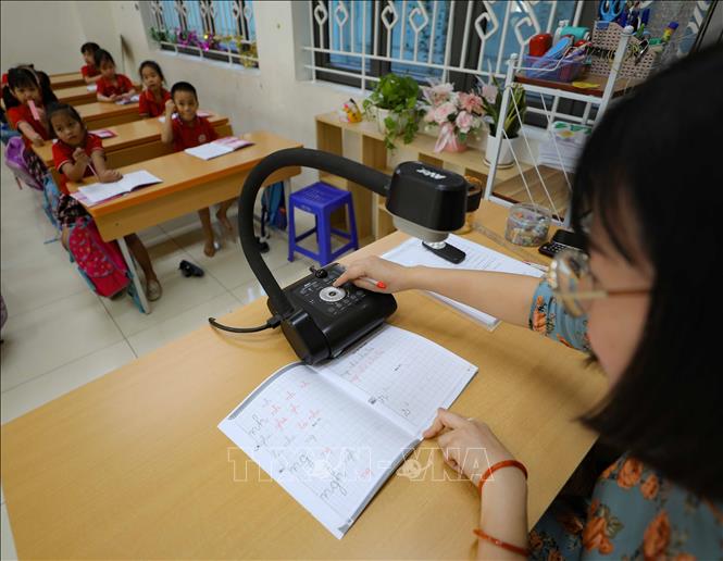 Giáo viên trường tiểu học Kim Đồng (quận Ba Đình) sử dụng máy soi bài giảng để trình chiếu lên màn hình lớn khi chữa bài cho học sinh trên lớp. Ảnh: Thanh Tùng - TTXVN