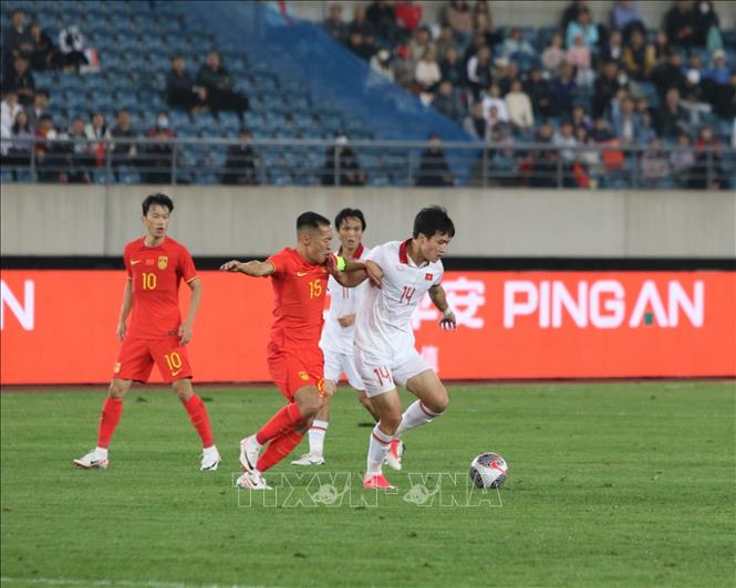 Tiền vệ Hoàng Đức (14) nỗ lực đi bóng trước sự theo kèm của cầu thủ Trung Quốc. Ảnh: TTXVN phát
