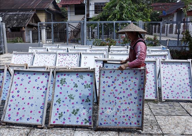 Giấy Saa sau khi được lên khung, trang trí được mang đi phơi nắng. Ảnh: Phạm Kiên - Phóng viên TTXVN tại Lào