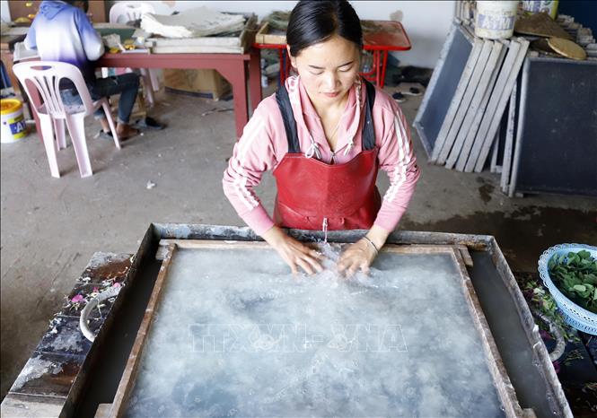 Công đoạn dàn bột giấy trên khuôn. Ảnh: Phạm Kiên - Phóng viên TTXVN tại Lào