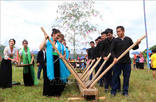 Cho lúa vào cối để giã thành cốm. Ảnh: Nguyễn Oanh-TTXVN