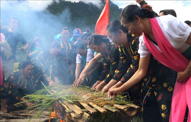 Sau khi cúng xong, lúa sẽ được nướng trên lửa để làm cốm. Ảnh: Nguyễn Oanh-TTXVN