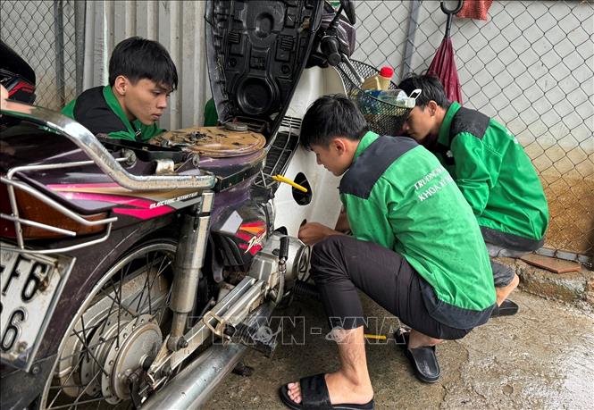 Đoàn Thanh niên Đại học Đông Á tham gia sửa miễn phí xe máy hỏng do ngập lụt cho người dân. Ảnh: Văn Dũng-TTXVN