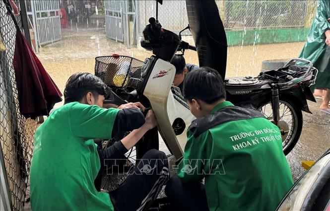 Đoàn Thanh niên Đại học Đông Á tham gia sửa miễn phí xe máy hỏng do ngập lụt cho người dân. Ảnh: Văn Dũng-TTXVN