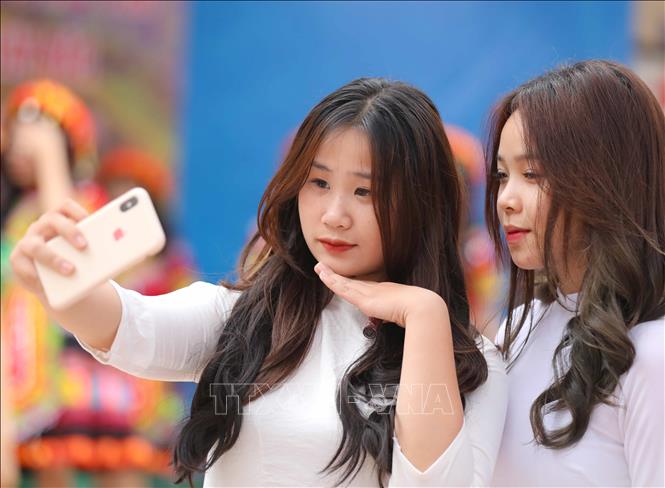 Chúng mình cùng lưu giữ lại khoảnh khắc đẹp trong tà áo dài trắng dưới nắng sân trường. Ảnh: Thanh Tùng - TTXVN