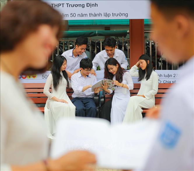 Nữ sinh trường THPT Trương Định, quận Hoàng Mai (Hà Nội), trong trang phục áo dài trắng cùng ôn bài với các bạn dưới sân trường. Ảnh: Thanh Tùng - TTXVN