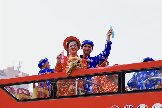 Xe buýt hai tầng đưa các cặp cô dâu, chú rể diễu hành qua những tuyến đường lớn Hồ Chí Minh. Ảnh: Hồng Giang - TTXVN