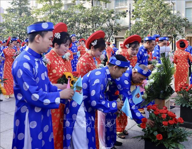 Các cặp vợ chồng thanh niên công nhân dâng hoa tại Tượng đài Chủ tịch Hồ Chí Minh. Ảnh: Hồng Giang - TTXVN