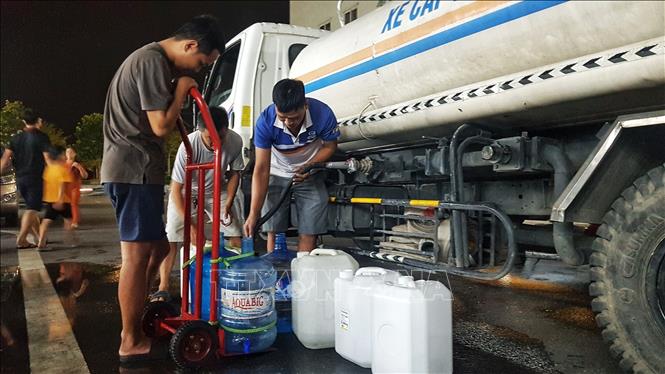 Người dân Khu đô thị Thanh Hà tận dụng mọi vật chứa và phương tiện để vận chuyển nước về gia đình (ảnh chụp tối 20/10). Ảnh: Phan Tuấn Anh - TTXVN