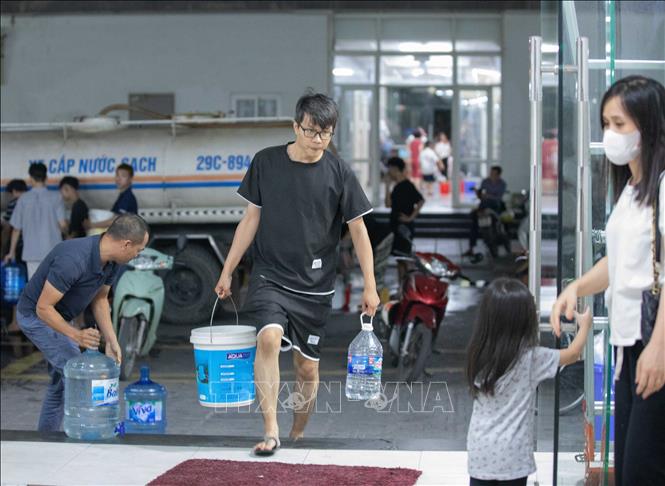 Người dân tận dụng mọi vật chứa để lấy nước về sử dụng. Ảnh: Hoàng Hiếu - TTXVN