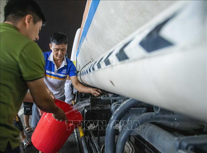 Người dân khu đô thị Thanh Hà lấy nước từ xe téc về sinh hoạt tối 20/10. Ảnh: Hoàng Hiếu - TTXVN
