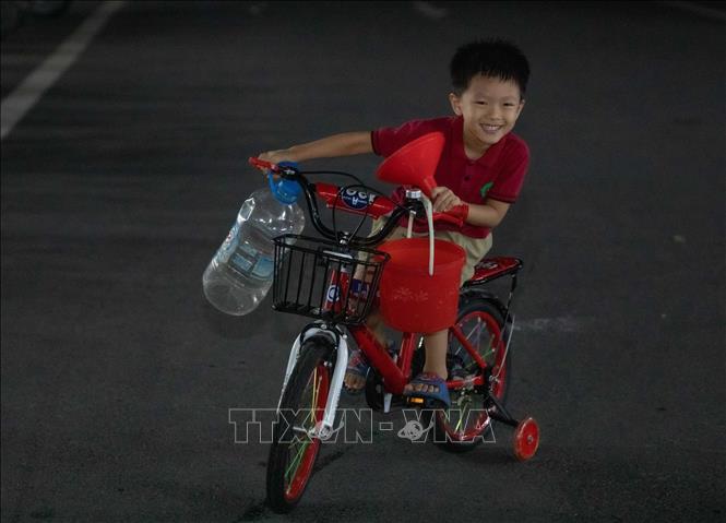 Một trẻ nhỏ với bình, xô, phễu để lấy nước cho gia đình. Ảnh: Hoàng Hiếu - TTXVN
