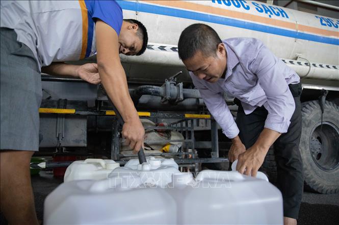 Người dân chứa nước vào can để đưa lên nhà. Ảnh: Hoàng Hiếu - TTXVN