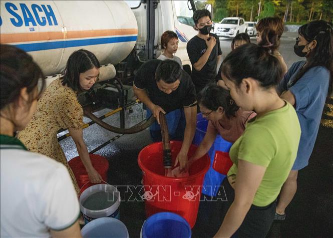 Đến gần 20h ngày 20/10, vẫn có nhiều người dân khu đô thị Thanh Hà xếp hàng chờ lấy nước. Ảnh: Hoàng Hiếu - TTXVN