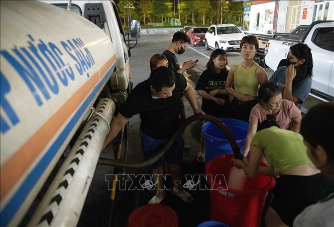 Đến gần 20h ngày 20/10, vẫn có nhiều người dân khu đô thị Thanh Hà xếp hàng chờ lấy nước. Ảnh: Hoàng Hiếu - TTXVN