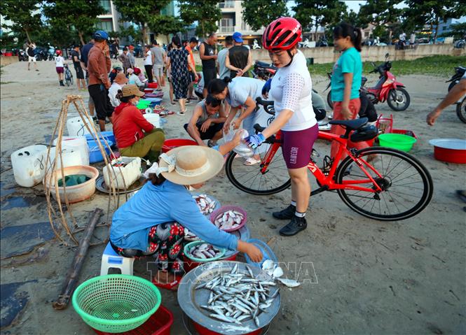 Một phụ nữ đi tập thể dục tranh thủ ghé chợ mua hải sản để nấu bữa ngon cho gia đình. Ảnh: Trần Lê Lâm – TTXVN 