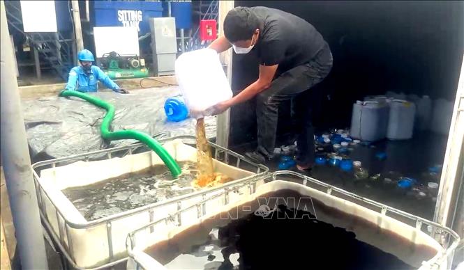 Lực lượng chức năng tiêu hủy số rượu không đảm bảo chất lượng. Ảnh: TTXVN phát