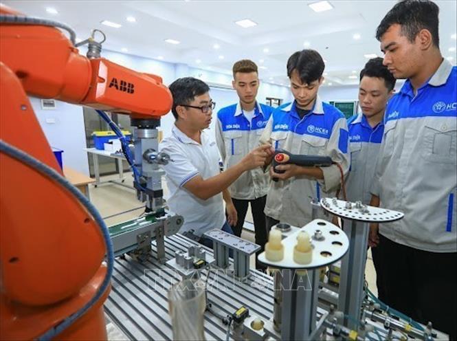 Thầy Lê Xuân Phong hướng dẫn sinh viên Lớp cơ điện tử 15 vận hành điều khiển cánh tay robot công nghiệp, lập trình mô phỏng robot trên PC. Ảnh: Hoàng Hiếu – TTXVN