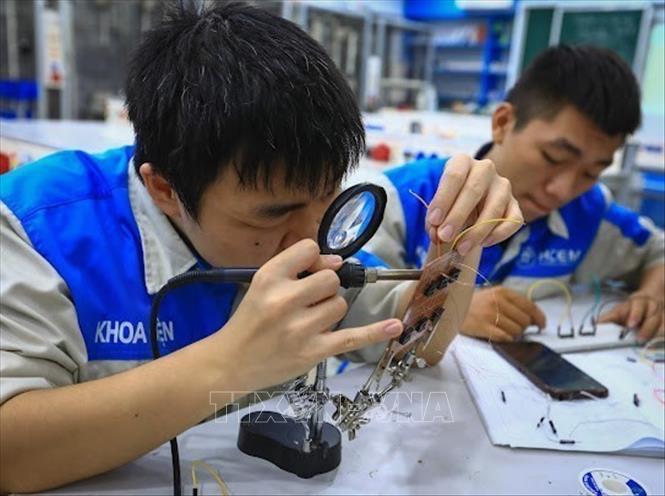 Sinh viên Lớp điện tử công nghiệp K16 hàn mạch robot tự thiết kế. Ảnh: Hoàng Hiếu – TTXVN