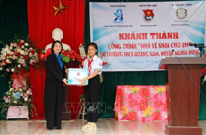 Phó Bí thư Tỉnh đoàn Nam Định Phạm Thị Thanh Huyền tặng quà cho đại diện học sinh Trường Trung học cơ sở Hoàng Nam. Ảnh: Nguyễn Lành - TTXVN 